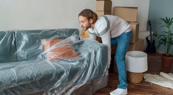 man-covering-furniture-with-plastic