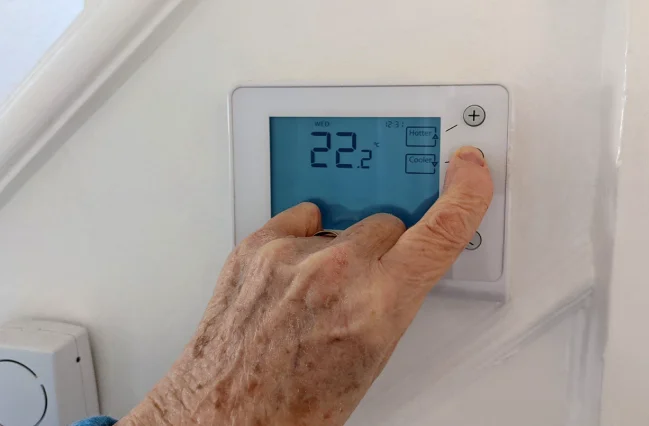 elderly-woman-is-increasing-the-wireless-thermostat-temperature