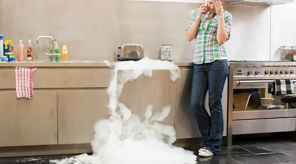 woman-is-on-the-phone-next-to-a-leaking-dishwasher