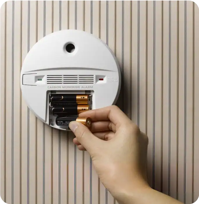 women changing batteries in a smoke alarm women changing batteries in a smoke alarm