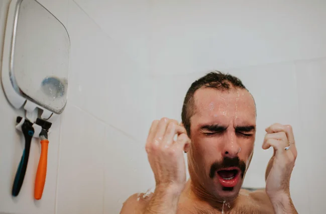 man-taking-a-bath-experiencing-an-electric-shower-going-hot-and-cold