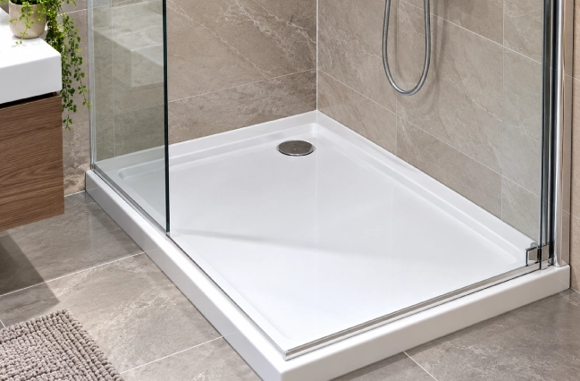 White shower tray installed in a modern bathroom with glass shower enclosure